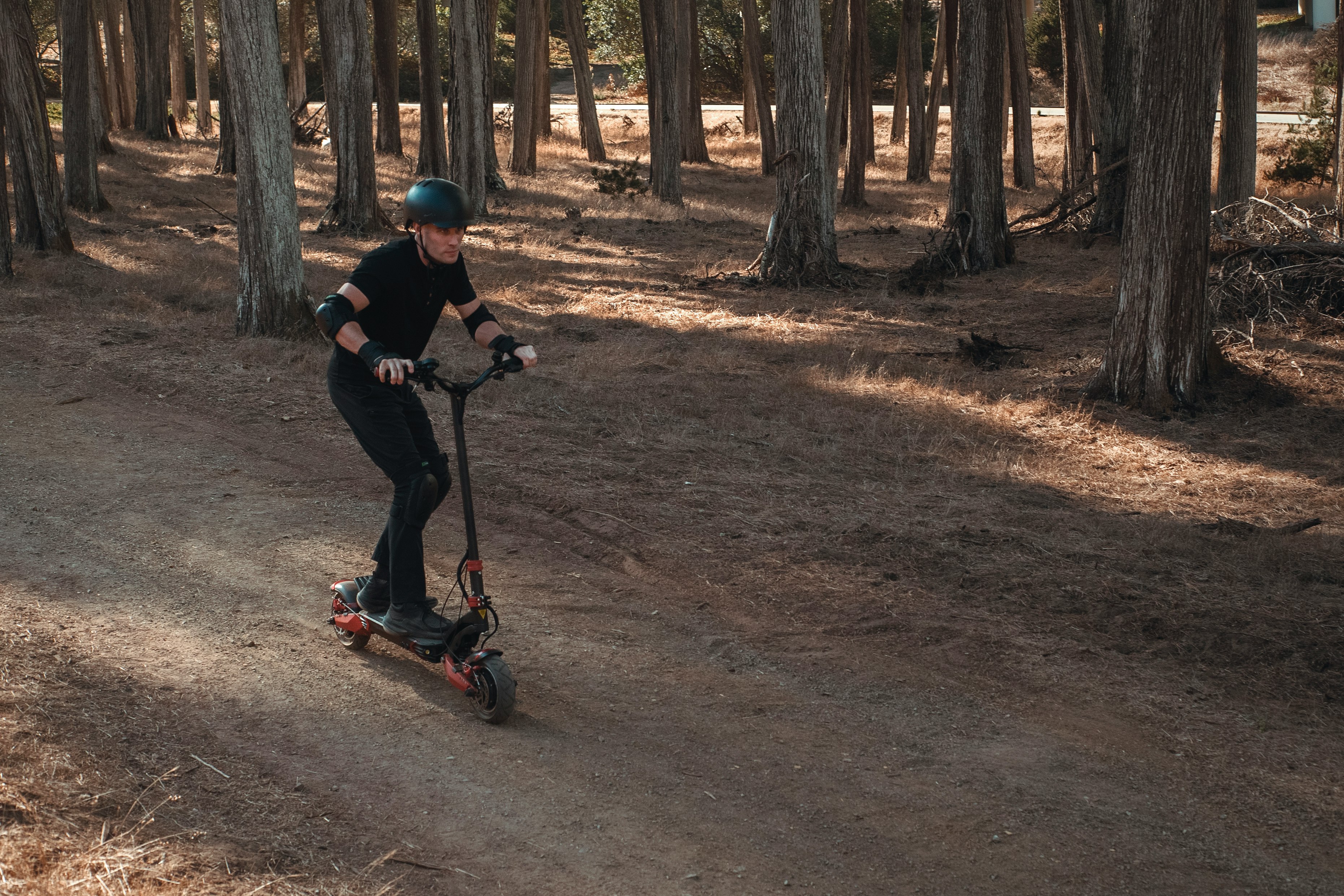 man in black shirt and pants riding red kick scooter